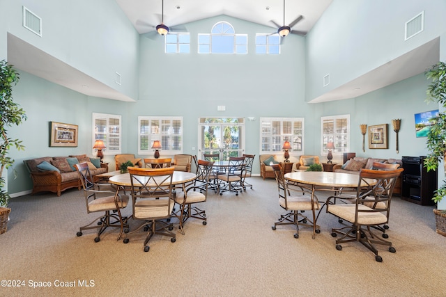 dining area featuring ceiling fan, high vaulted ceiling, and light colored carpet