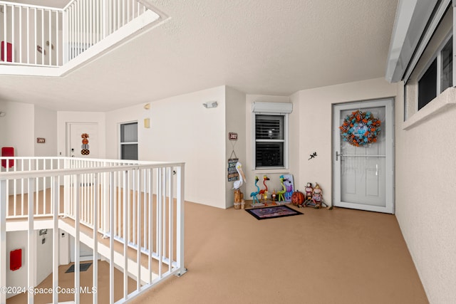 hall featuring a textured ceiling and a wall unit AC