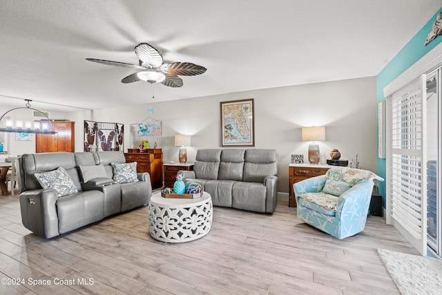 living room featuring ceiling fan, light hardwood / wood-style floors, and a textured ceiling