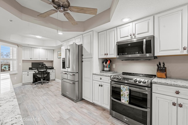 kitchen featuring white cabinets, stainless steel appliances, and a tray ceiling