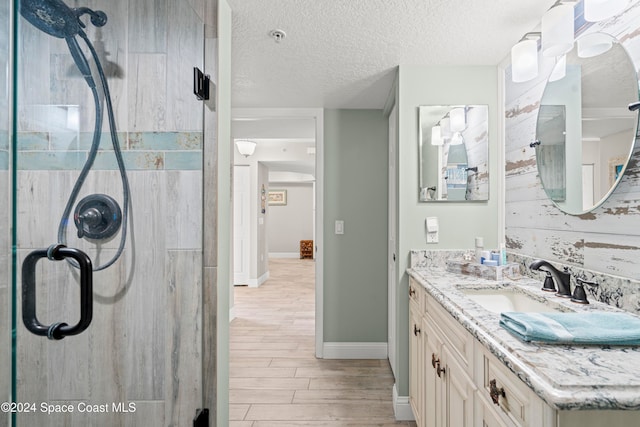 bathroom featuring a textured ceiling, vanity, hardwood / wood-style flooring, and an enclosed shower