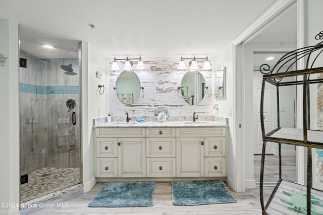 bathroom featuring hardwood / wood-style flooring, vanity, a shower with shower door, and a textured ceiling