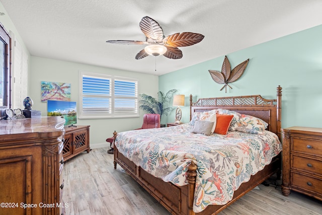 bedroom with ceiling fan, light wood-type flooring, and a textured ceiling