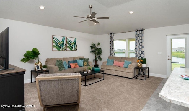 carpeted living room with a water view and ceiling fan