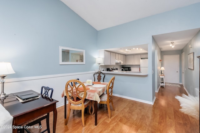 dining room with light wood-type flooring and vaulted ceiling