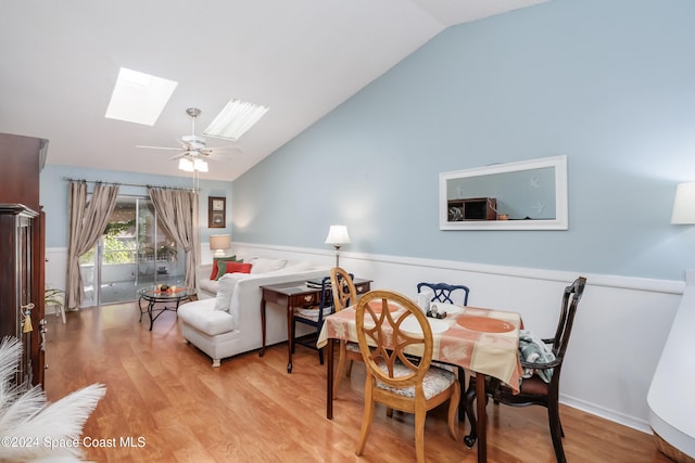 dining room with ceiling fan, light wood-type flooring, and lofted ceiling with skylight