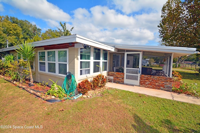 view of front of home featuring a sunroom, a front lawn, and a carport