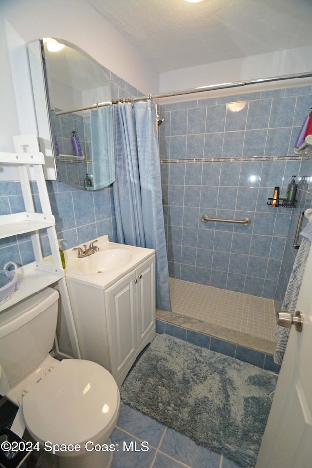 bathroom featuring vanity, tile patterned flooring, toilet, tile walls, and curtained shower