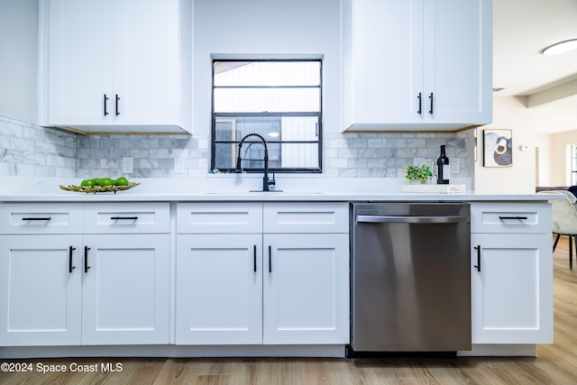 kitchen with sink, stainless steel dishwasher, decorative backsplash, light wood-type flooring, and white cabinetry