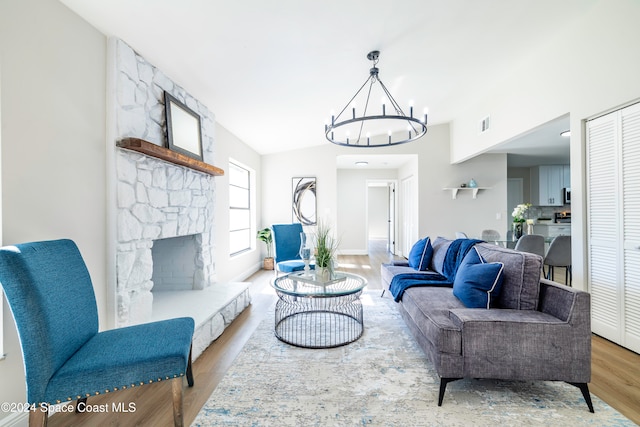 living room featuring a chandelier, vaulted ceiling, light hardwood / wood-style flooring, and a fireplace