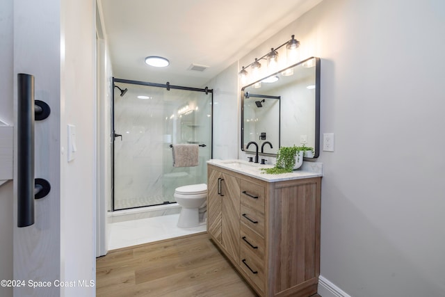 bathroom with hardwood / wood-style floors, vanity, toilet, and walk in shower