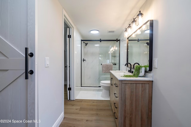 bathroom featuring hardwood / wood-style floors, vanity, a shower with door, and toilet