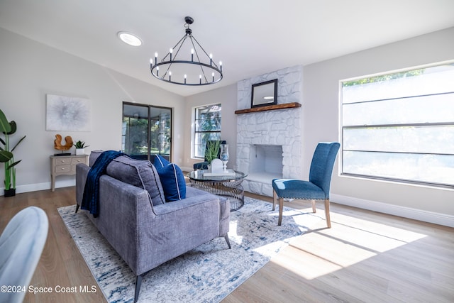 living room with a chandelier, a wealth of natural light, a fireplace, and light hardwood / wood-style floors