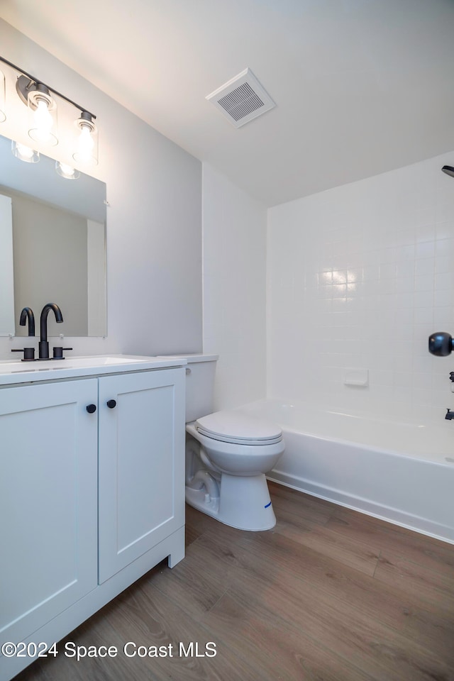 full bathroom featuring hardwood / wood-style flooring, vanity, toilet, and tiled shower / bath combo