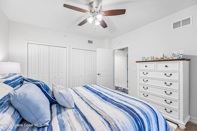 bedroom featuring carpet flooring, ceiling fan, and multiple closets