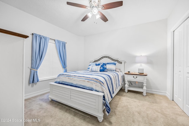 carpeted bedroom featuring ceiling fan and a closet