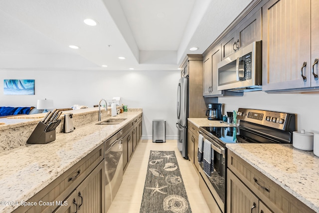 kitchen with light stone counters, sink, and appliances with stainless steel finishes