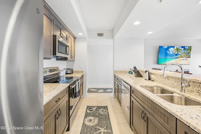 kitchen with light stone counters, sink, and appliances with stainless steel finishes