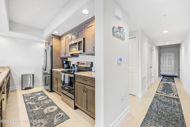 kitchen with light stone countertops and appliances with stainless steel finishes