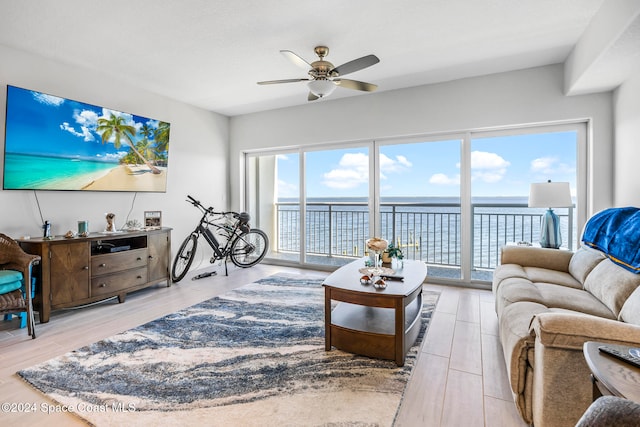 living room with ceiling fan, light hardwood / wood-style flooring, and a water view