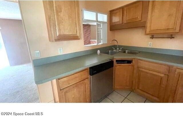 kitchen with dishwasher, light tile patterned floors, and sink