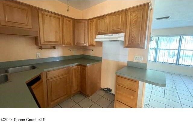 361 Payne Ave, Cocoa, FL 32927 - kitchen featuring under cabinet range hood, light tile patterned floors, and brown cabinetry