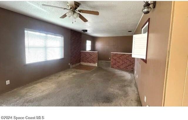 361 Payne Ave, Cocoa, FL 32927 - unfurnished living room with carpet, a textured ceiling, and ceiling fan