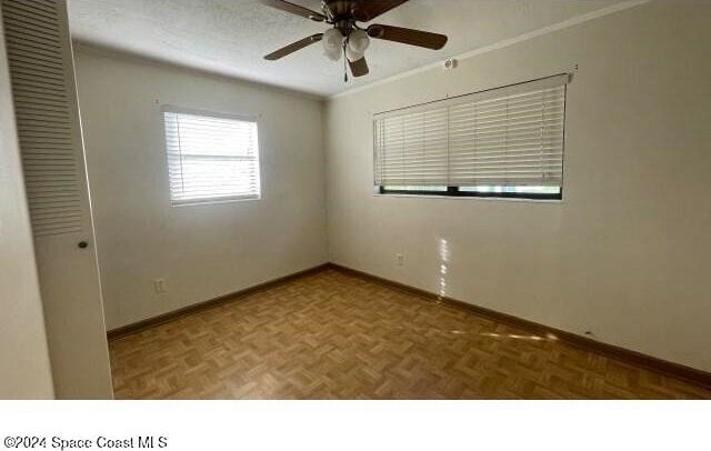 spare room featuring crown molding, parquet floors, a textured ceiling, and ceiling fan