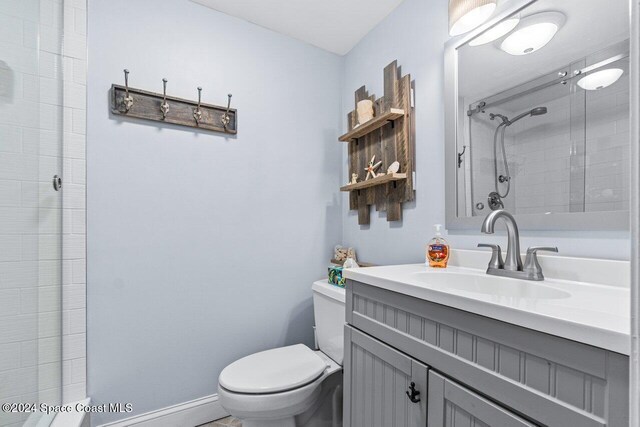 bathroom with a tile shower, vanity, and toilet