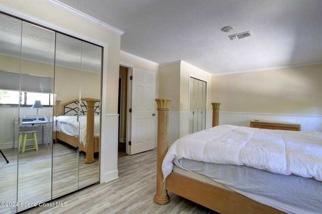 bedroom with hardwood / wood-style floors, ornamental molding, and a textured ceiling