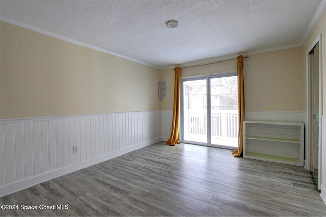 spare room with a textured ceiling, light hardwood / wood-style flooring, and ornamental molding