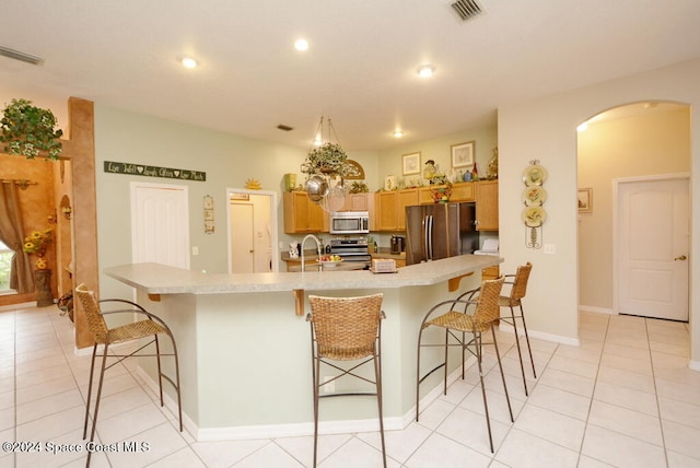 kitchen featuring a kitchen bar, a large island, light tile patterned floors, and stainless steel appliances