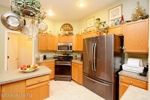 kitchen with light brown cabinets, light tile patterned floors, and appliances with stainless steel finishes