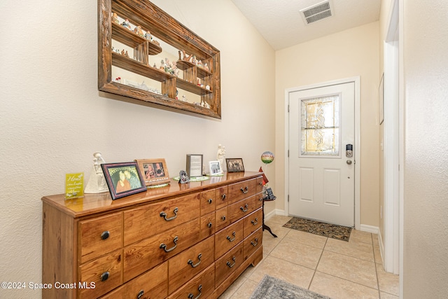 doorway featuring light tile patterned flooring and a textured ceiling