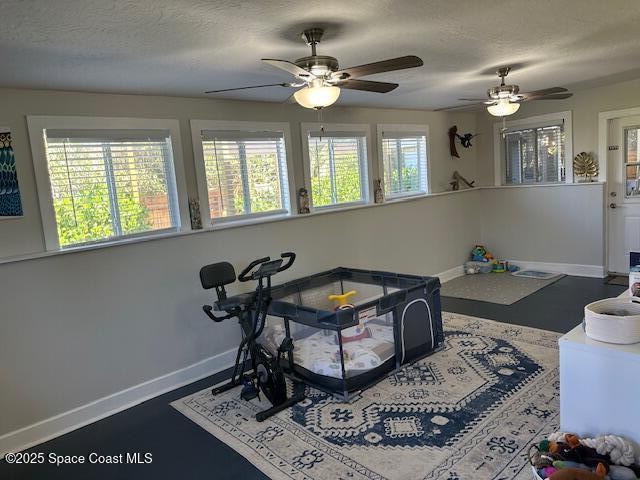 playroom with ceiling fan and a textured ceiling