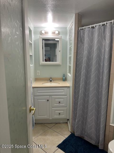 bathroom featuring vanity, tile patterned floors, toilet, a textured ceiling, and curtained shower