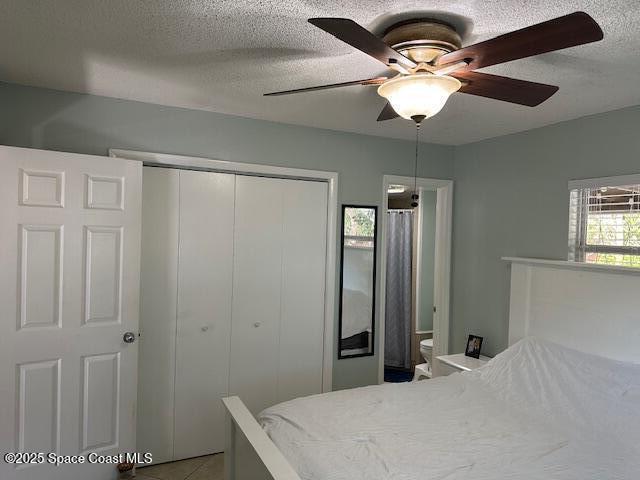 tiled bedroom with ceiling fan, a closet, and a textured ceiling