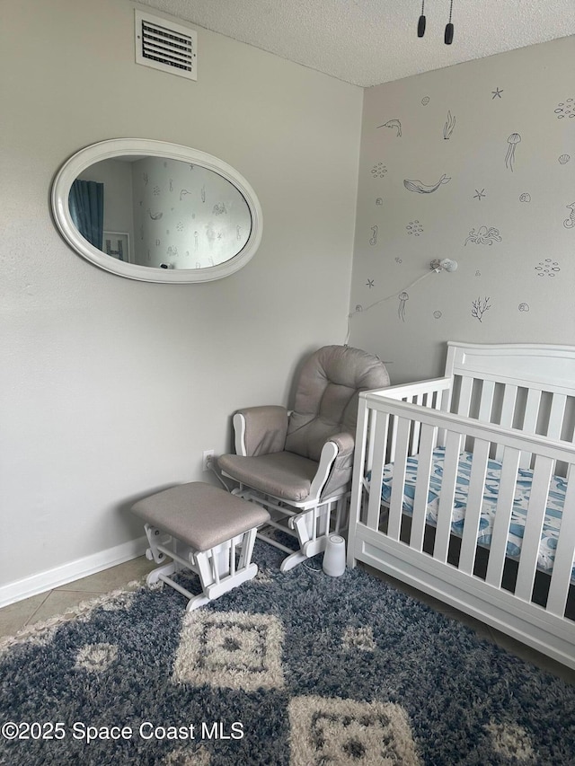 bedroom with a crib and a textured ceiling