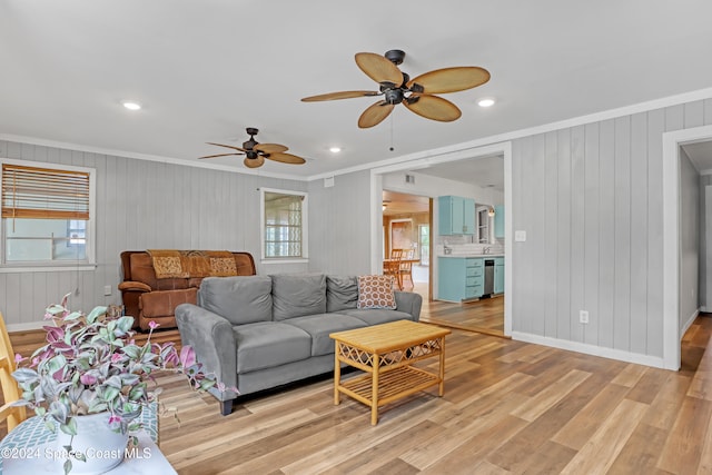 living room with ceiling fan, light hardwood / wood-style flooring, wooden walls, and ornamental molding