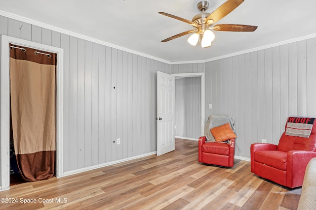 sitting room with wooden walls, light hardwood / wood-style flooring, and crown molding