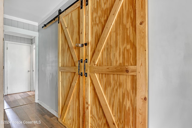 details featuring wood-type flooring, a barn door, and wooden walls