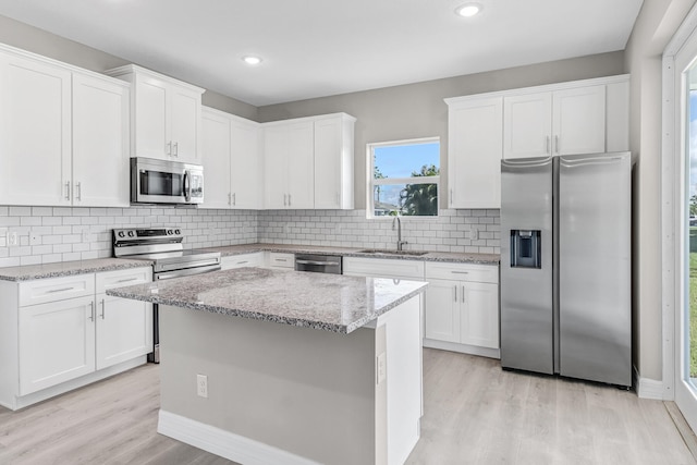 kitchen with sink, stainless steel appliances, light hardwood / wood-style floors, decorative backsplash, and white cabinets