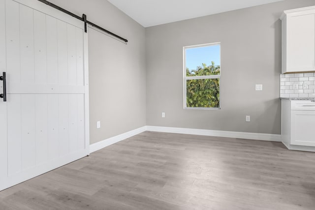 unfurnished bedroom featuring light wood-type flooring and a barn door