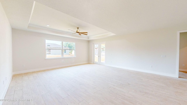 empty room featuring light hardwood / wood-style floors, a raised ceiling, and ceiling fan