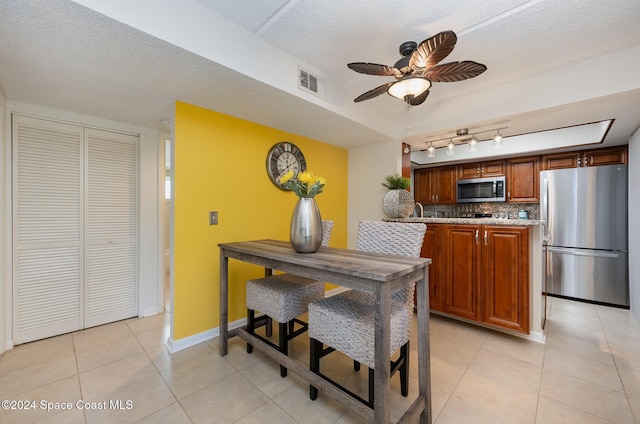 641 Ridge Club Dr Unit 21, Melbourne, FL 32934 - kitchen with appliances with stainless steel finishes, backsplash, ceiling fan, light tile patterned flooring, and brown cabinetry