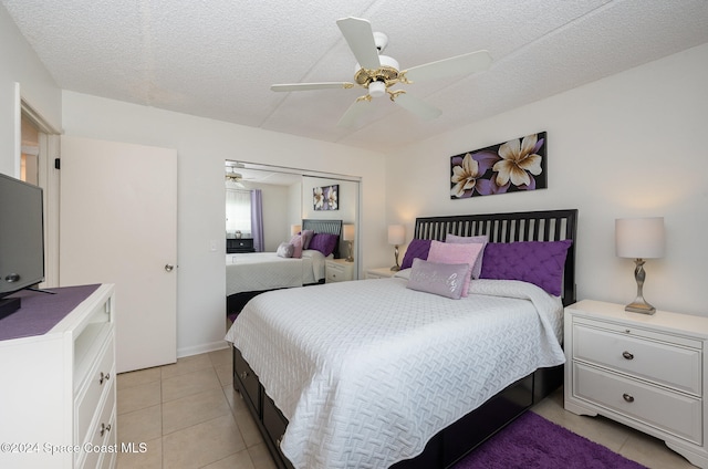 bedroom with ceiling fan, light tile patterned floors, a textured ceiling, and a closet