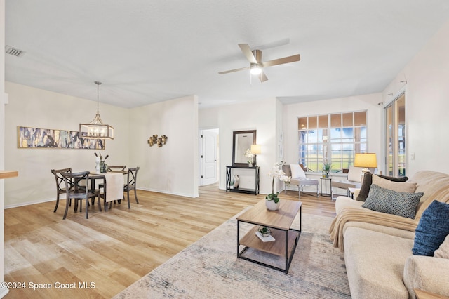 living room featuring ceiling fan with notable chandelier and wood-type flooring