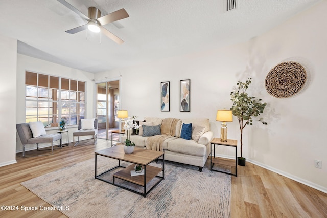 living room featuring a textured ceiling, light hardwood / wood-style flooring, and ceiling fan