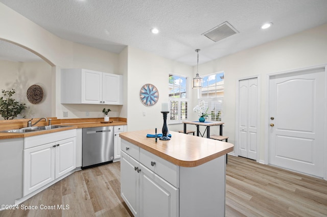 kitchen featuring dishwasher, wooden counters, white cabinetry, and hanging light fixtures