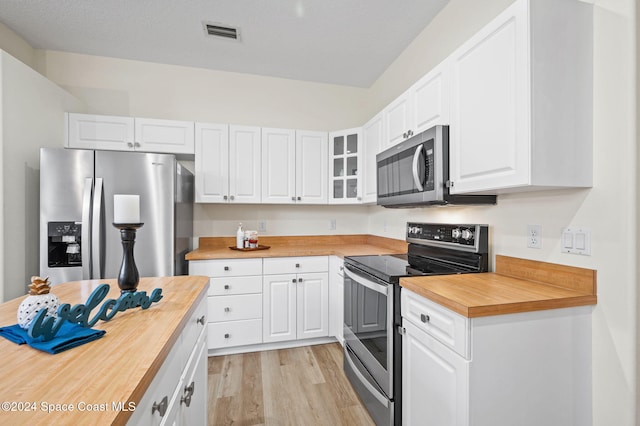 kitchen featuring butcher block counters, white cabinetry, light hardwood / wood-style flooring, and appliances with stainless steel finishes